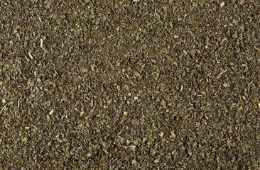 Dried and chopped up basil spice pile background, top view