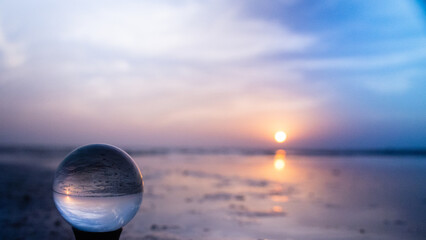 Crystal lens ball at the beach on North Padre Island National Seashore in Texas at sunrise in blues and pinks. Glass photography ball reflecting the colors of the sunrise. 