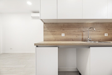 a kitchen with white cabinets and oak countertops with matching backsplashes in an empty loft style...