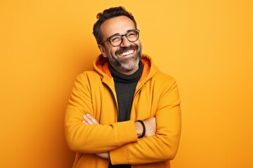 Portrait of happy mature man in yellow hoodie and glasses on yellow background