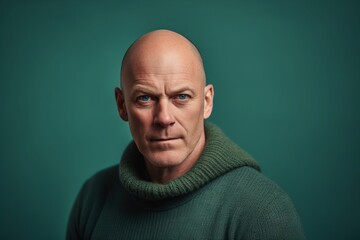 Portrait of a bald man in a green sweater on a green background