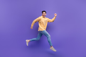 Fototapeta na wymiar Full size photo of attractive young man running fast hurry shopping wear trendy yellow clothes isolated on violet color background