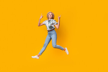 Fototapeta na wymiar Full length photo of adorable gorgeous woman wear blouse denim pants jumping showing rock symbol isolated on yellow color background