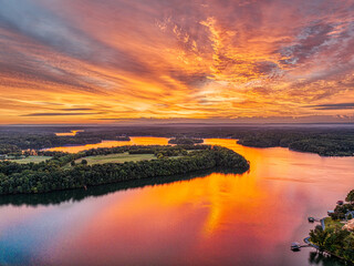 Aerial view of a beautiful orange morning sunrise sky and water reflection over the lake and golf...