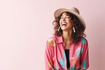 Portrait of beautiful young woman in hat and shirt on pink background