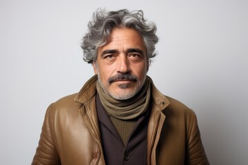 Portrait of a handsome Indian man with grey hair and beard wearing a brown leather jacket.