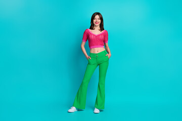 Full length photo of positive cheerful woman dressed knitwear top green pants keep arms in pockets...