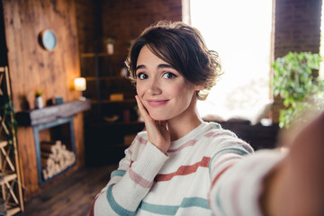 Photo of adorable peaceful girl hand touch cheek take selfie sunlight window pastime modern apartment inside - obrazy, fototapety, plakaty