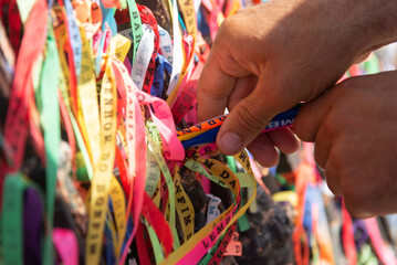 People are seen paying homage to Senhor do Bonfim by tying a souvenir ribbon on the church's iron railing. City of Salvador, Bahia.