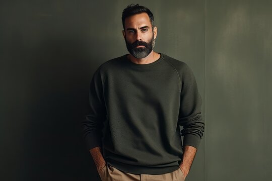 Handsome bearded man in a green sweater on a dark background
