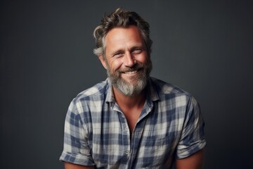 Portrait of a happy mature man with beard and mustache in casual shirt on grey background.
