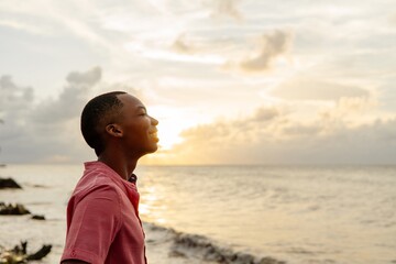 Young adult black man breathing fresh air on the beach	
