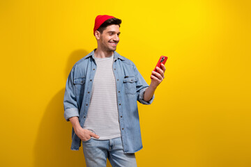 Photo of good mood funky man dressed jeans shirt communicating modern gadget empty space isolated yellow color background