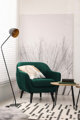 Comfortable armchair, lamp and table in stylish room