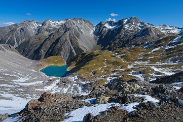 Breathtaking Blue Lake Amidst Snowy Rocky Mountains along Robert Ridge Route, New Zealand