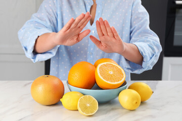 Woman suffering from food allergies refusing eat citrus fruits at light marble table indoors,...