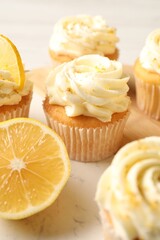 Tasty cupcakes with cream and lemon zest on board, closeup