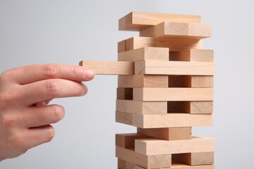 Woman playing Jenga on light gray background, closeup