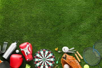 Different sport equipment on green grass, flat lay. Space for text