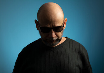 Obraz premium Portrait of bald and bearded mature man in sunglasses looking down.