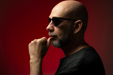 Handsome, bald and bearded man in sunglasses, serious and confident posing for photo.