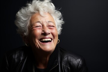 Portrait of a happy senior woman laughing against a dark background.