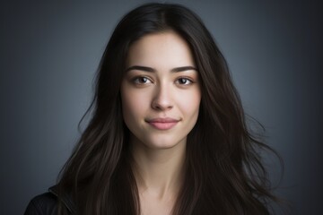 Portrait of a beautiful young woman with long brown hair on a gray background