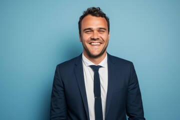 Portrait of happy young businessman in suit and tie on blue background