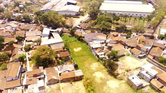 Drone footage. Aerial video of Residential Area in Suburban Village in West Java - Indonesia. The slopes and valleys are filled with residential areas and rice fields. 