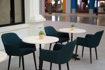 A background image of an empty interior with round tables and cozy chairs in a shopping center, copy space