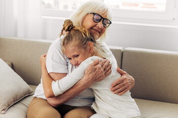Child girl hugging grandmother granddaughter couch