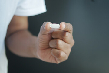 Close up of man hand holding capsule against orange background 