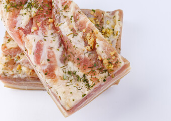Appetizing salty lard with layers of meat with garlic and herbs. Two pieces of salted lard on a white background.