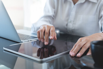 Businesswoman using digital tablet with laptop computer on office table, close up. Business woman surfing the internet, searching the information