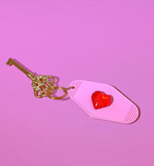 A Gold Skeleton Key with a Heart Shaped Hotel Room Tag, Key to Love Concept, Keys to My Heart, Valentine's Day on a Pink Background