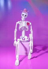 A Human Skeleton Sitting with a Big Red Heart Popping Out of Chest, Love Concept, Valentine's Day, Halloween on a Purple Background