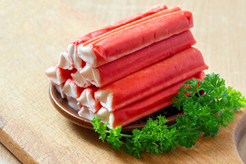 A bunch of crab sticks with parsley on a background of wood. Crab sticks with herbs.