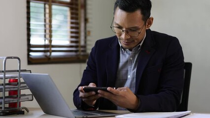 Happy businessman is using smartphone to text with his friends.