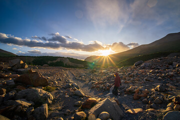 A woman walking with beautiful sunrise with sun flare in Agostini campground in the morning (Patagonia, Argentina)