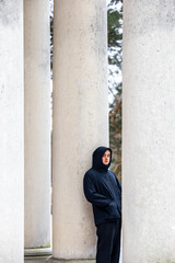 Stockholm, Sweden A young man stands between columns  in the Woodlawn Cemetery, or Skogskyrkogarden, a Unesco World Heritage site, in winter.