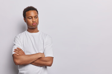 Sulking upset dark skinned man keeps arms folded being dissatisfied with something has sad...