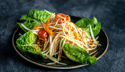 Spicy thai green papaya salad served with lettuce and tomato.