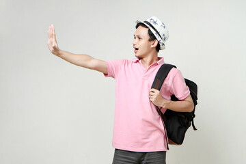 Asian man backpacker showing his palm hand. giving stop gesture. digital nomad and travelling...