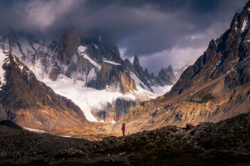 A tiny woman standing alone in the Agostini campsite surrounded by mountain range in the morning...