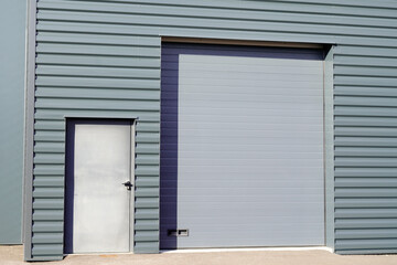 entrance roll-down facade shutters on gray building fire exit door in commercial industrial unit