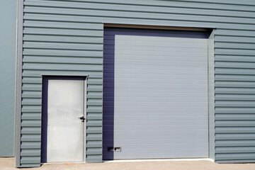 Fototapeta premium entrance roll-down facade shutters on gray building fire exit door in commercial industrial unit