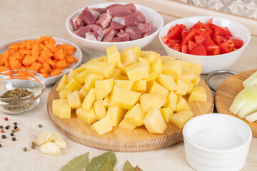 Prepared raw ingredients for cooking stewed potatoes with meat in multi cooker in kitchen on a table. Cooking stewed potato with meat in multicooker.