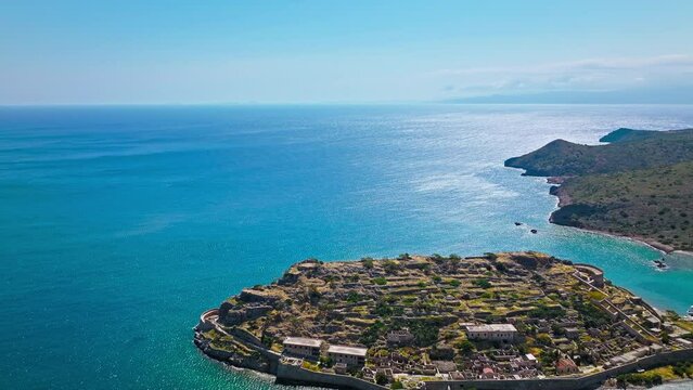 Scenic Aerial view of antique Fortress Island in Crete, Greece with tourists visiting. Spinalonga barren arid rocky islet in Elounda. Venetians built bastion-type seaward fortresses in Mediterranean