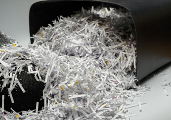 Zutylizowane papierowe dokumenty, ścinki papieru wysypują się z niszczarki 