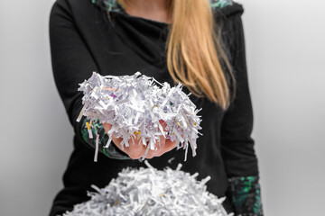 Zniszczone dokumenty firmowe, kobieta trzyma w dłoni ścinki papieru z niszczarki 